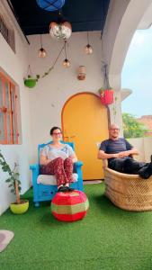 two people sitting in chairs in a room with grass at Manavi Home Stay in Mathura