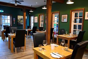 un restaurante con mesas y sillas de madera y paredes verdes en Lime Tree Hotel, en Fort William
