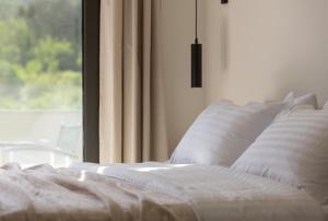 Bett mit weißen Kissen vor dem Fenster in der Unterkunft ENARIA in Nafplio