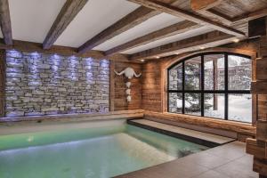 a pool in a room with a stone wall at Chalet Papillon - LES CHALETS COVAREL in Val dʼIsère