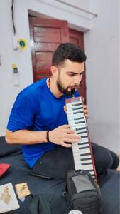 a man sitting on a bed playing a keyboard at Manavi Hostel Near by Mathura Railway Station in Mathura