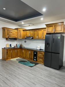a kitchen with wooden cabinets and a black refrigerator at Căn hộ 03 phòng ngủ tầng 8 Oasky view biển in Vung Tau