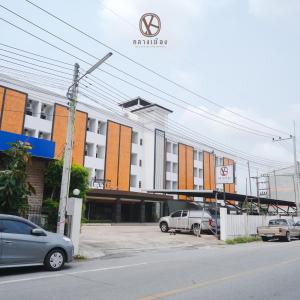 um parque de estacionamento com carros estacionados em frente a um edifício em Klaang Muang Hotel (โรงแรมกลางเมือง) em Rayong