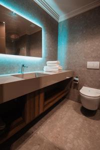een badkamer met een wastafel, een toilet en een spiegel bij ROYAL G DELUXE in Durrës