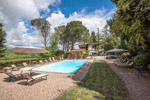 einen Pool mit Stühlen und Sonnenschirmen neben einem Haus in der Unterkunft Appartamento Blu in Asciano