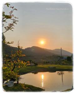 a sunset over a lake with the sun setting in the background at Nex Station Kanchanaburi in Kanchanaburi