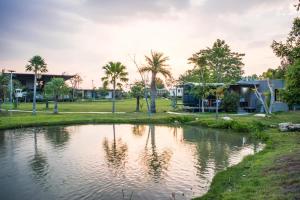 a pond in a park with palm trees and houses at Nex Station Kanchanaburi in Kanchanaburi
