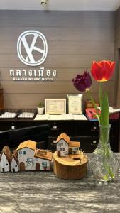una mesa con un jarrón de flores y casas en ella en Klaang Muang Hotel (โรงแรมกลางเมือง), en Rayong