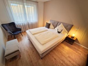 a bedroom with a large bed and a chair at Luxus mit Schwarzwaldromantik pur! in Ottenhöfen