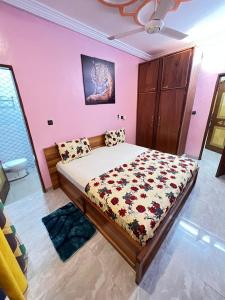 ein Schlafzimmer mit einem Bett in einem Zimmer mit rosa Wänden in der Unterkunft FS service in Ouagadougou