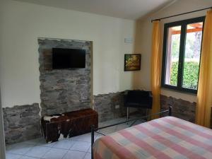 ein Schlafzimmer mit einer Steinmauer und einem Flachbild-TV in der Unterkunft Toskana Relax in Fucecchio