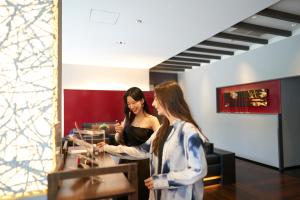 two women standing in a store looking at a mirror at Hotel Resol Trinity Kanazawa in Kanazawa