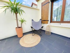 a patio with a chair and palm trees and a rug at TEA&CHILL - Manhattan home - proche gare in Tremblay En France
