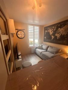 salon z kanapą i zegarem na ścianie w obiekcie Charmant appartement F1 w mieście Saint-Dizier