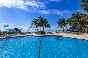 a pool at the resort with palm trees and umbrellas at The Reef Playacar Beach Resort & Spa-Optional All Inclusive in Playa del Carmen
