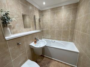 a bathroom with a tub and a sink and a toilet at Millgrove House Apartments in Eastbourne +38 photos