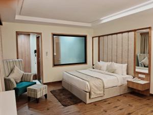 a bedroom with a large bed and a chair at Cilantro Comfort Jaipur in Jaipur