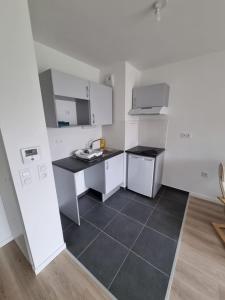 a kitchen with white cabinets and a black tile floor at Flat Bobigny near Paris 1 min from the metro in Bobigny