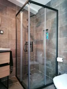 una doccia con porta in vetro in bagno di Casa do Favinha a Machico