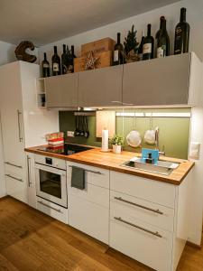 cocina con armarios blancos y encimera con fregadero en Grünseeappartement en Turracher Hohe