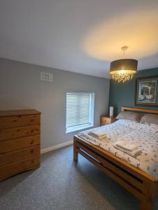 - une chambre avec un lit, une commode et un lustre dans l'établissement Blue Bell Apartment, à Kidsgrove