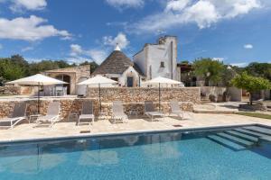 a pool with chairs and umbrellas in front of a house at Trulli Tower in Putignano