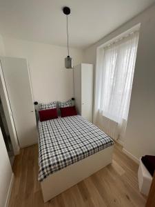 - une chambre avec un lit doté d'oreillers rouges et une fenêtre dans l'établissement Appartement cosy à 1 min de Paris, à Charenton-le-Pont