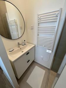 La salle de bains blanche est pourvue d'un miroir et d'un lavabo. dans l'établissement Appartement cosy à 1 min de Paris, à Charenton-le-Pont