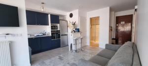 a kitchen with blue cabinets and a couch in a living room at Juan-Les-Pins 150m des plages 6 couchages Parking in Juan-les-Pins