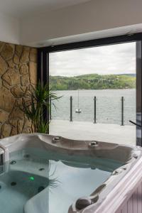 a bath tub with a view of the water at NOI Resort SPA - woda i las in Tęgoborze