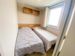 - une petite chambre avec 2 lits et une fenêtre dans l'établissement Mobile-home MAZET 93 à Vias, à Vias