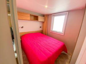 - un lit rouge dans une petite chambre avec fenêtre dans l'établissement Mobile-home MAZET 93 à Vias, à Vias
