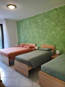 sypialnia z 2 łóżkami i zieloną ścianą w obiekcie Hotel del Falco w mieście Gravedona