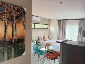 a bedroom with a bed and a painting of trees at De Guest @115 in Centurion