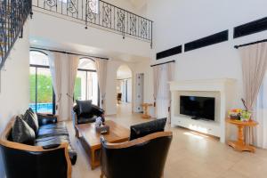 a living room with a couch and a tv at Estella Pool Villas Pattaya Formerly Chivani Pattaya in Na Jomtien