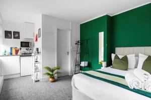 Livestay Affordable En-Suite Studio Rooms in London, N14 في East Barnet: غرفة نوم خضراء وبيضاء مع سرير ومطبخ