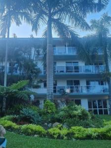 a large building with palm trees in front of it at Your Coral Coast Resort Inn in Palm Cove