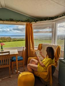 a young girl sitting in a chair reading a book at Escape to the Mountain in Halkyn