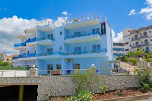 een wit gebouw met blauwe balkons en een brug bij Hotel Esmerald Ksamil in Ksamil