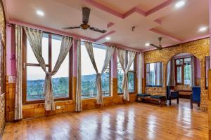 ein leeres Wohnzimmer mit großen Fenstern und Holzböden in der Unterkunft The Onyx Abode in Dharamsala