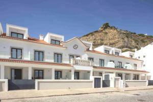 a large white building with a mountain in the background at Paradise bay T3 in São Martinho do Porto