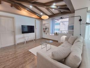 sala de estar con sofá blanco y TV de pantalla plana en [ COM,A stay] Hongdea St 5min / 3room, en Seúl