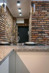 a kitchen with two wine glasses and a brick wall at Fancy Apartment Nikiszowiec in Katowice