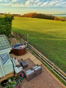 a woman in a hot tub on a deck with a field at Escape to the Mountain in Halkyn