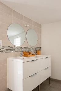 ein Badezimmer mit einem weißen Waschbecken und 2 Spiegeln in der Unterkunft Apparemment départ GR20 in Calenzana