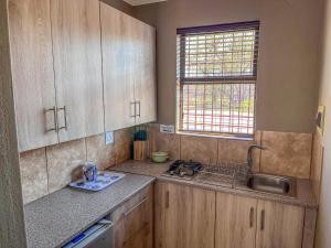 a kitchen with wooden cabinets and a sink and a window at My Africa Adventure Farm in Hoedspruit +71 photos