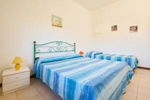 1 dormitorio con 2 camas con sábanas de rayas azules en Mare Etrusco Villetta D2, en Populonia