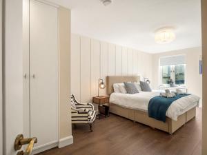 um quarto com uma cama, uma cadeira e uma janela em The Executive at Clifden Boutique Apartments em Clifden