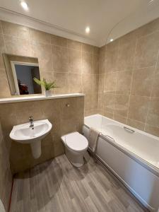 a bathroom with a sink and a toilet and a bath tub at Millgrove House Apartments in Eastbourne