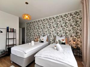 two beds in a bedroom with a wallpaper at BohnApartments Haus Zocheblick - 2 kostenlose Parkplätze - sehr ruhig - 4 Schlafzimmer - Neubau - Vollausstattung - WLAN in Hoppegarten